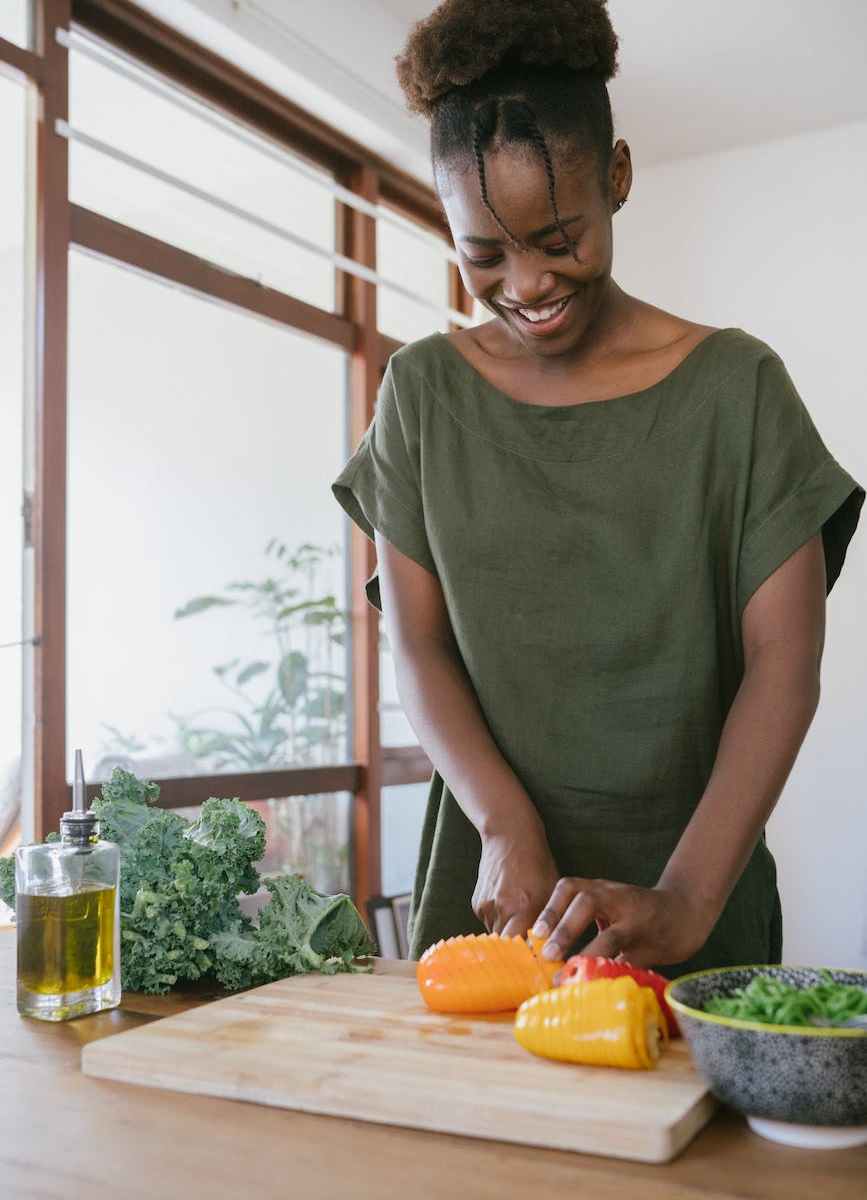 woman in green tank top holding orange bell pepper